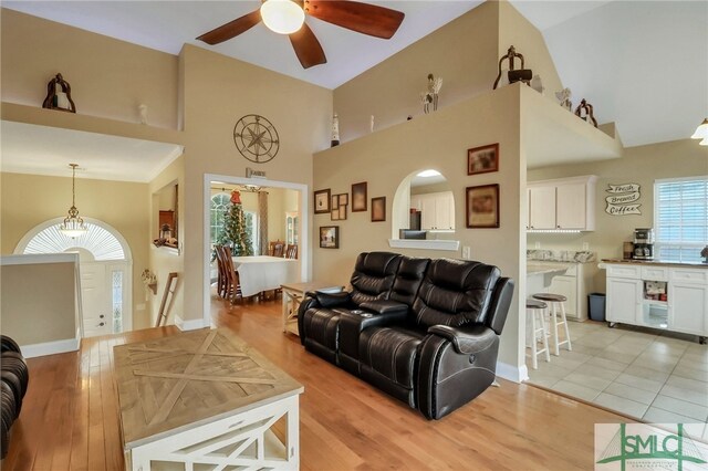 living room with ceiling fan, high vaulted ceiling, and light hardwood / wood-style floors