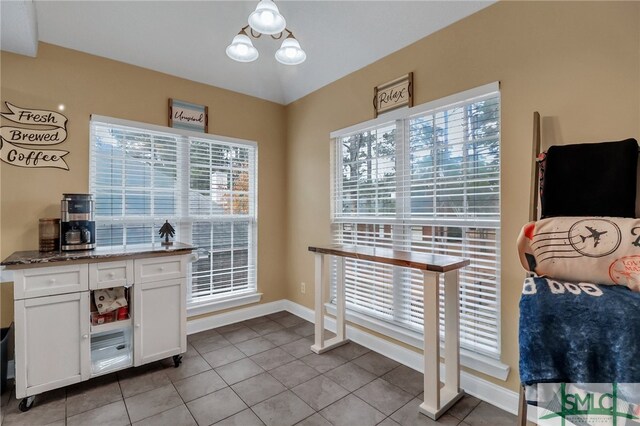 interior space featuring stone counters, white cabinets, a chandelier, and light tile patterned floors