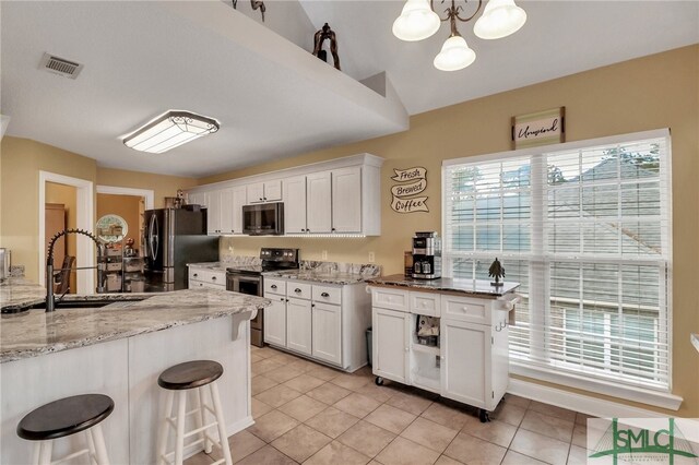 kitchen with appliances with stainless steel finishes, vaulted ceiling, white cabinetry, and pendant lighting