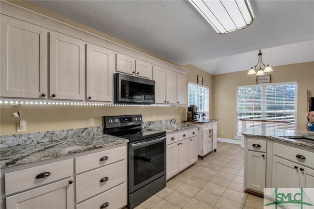 kitchen featuring white cabinets, stainless steel appliances, light stone countertops, and a notable chandelier