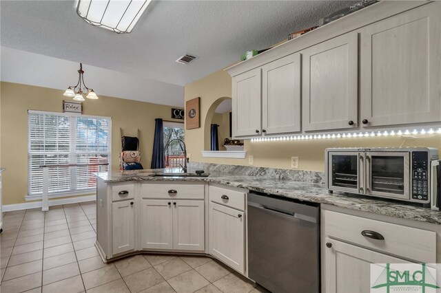 kitchen featuring sink, an inviting chandelier, light stone counters, a textured ceiling, and appliances with stainless steel finishes