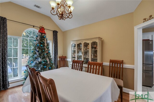 dining area featuring light hardwood / wood-style floors, lofted ceiling, and a notable chandelier