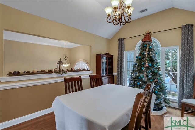 dining room featuring a chandelier, plenty of natural light, hardwood / wood-style floors, and lofted ceiling