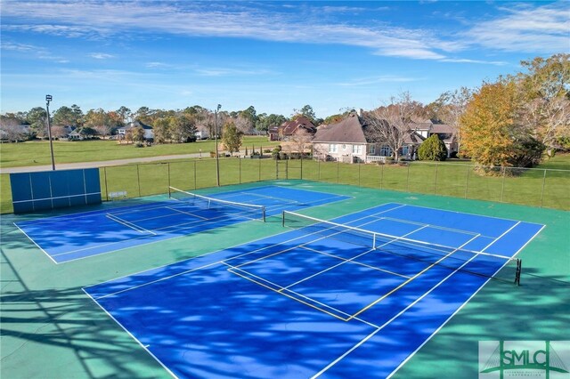 view of tennis court with a yard and basketball hoop