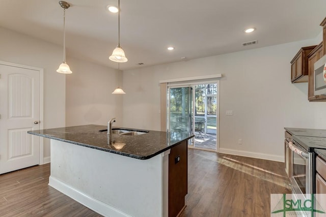 kitchen featuring dark stone counters, sink, electric range, dark hardwood / wood-style floors, and hanging light fixtures