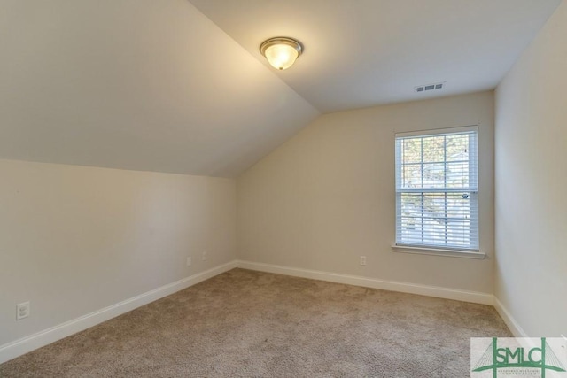 additional living space featuring light carpet and vaulted ceiling