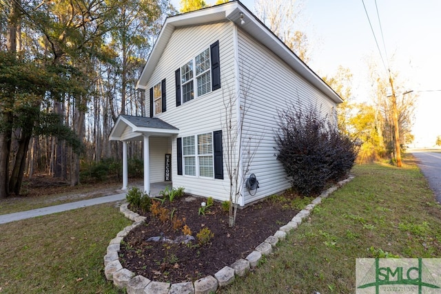 view of side of home featuring a lawn and covered porch