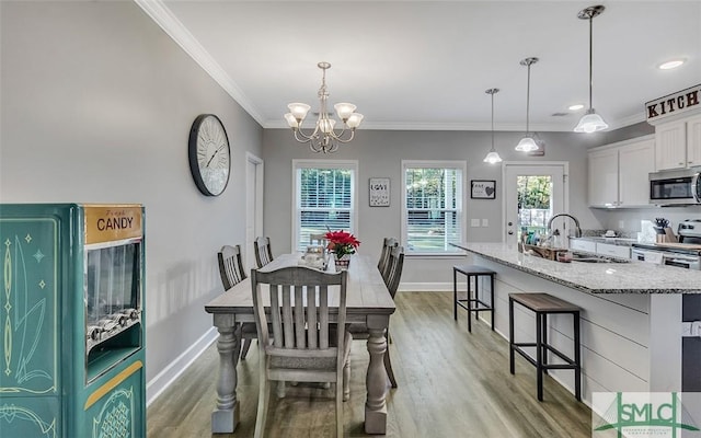 dining room featuring crown molding, sink, a notable chandelier, and hardwood / wood-style flooring