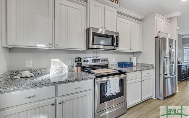 kitchen featuring white cabinetry, crown molding, appliances with stainless steel finishes, and light hardwood / wood-style flooring