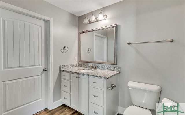 bathroom featuring toilet, vanity, and hardwood / wood-style flooring