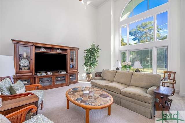 living room featuring light carpet, a towering ceiling, and crown molding