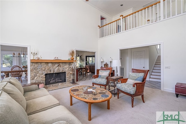 living room featuring a stone fireplace, light colored carpet, ornamental molding, and a high ceiling