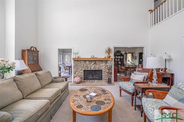 living room featuring carpet flooring, a stone fireplace, and a towering ceiling