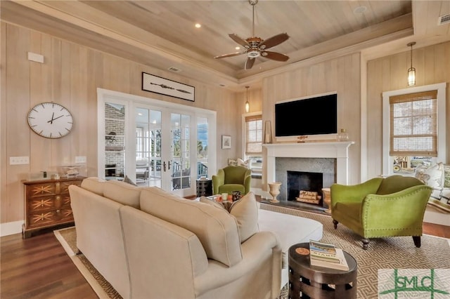 living room with ceiling fan, dark wood-type flooring, a tray ceiling, and french doors