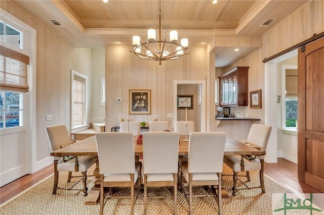 dining space featuring a barn door, plenty of natural light, an inviting chandelier, and light hardwood / wood-style flooring