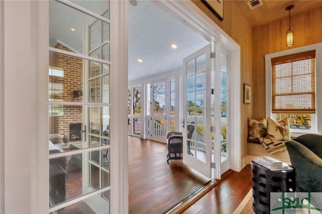 doorway to outside featuring wood walls, wood-type flooring, a towering ceiling, and french doors