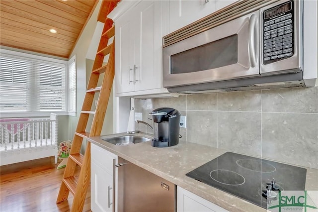 kitchen featuring hardwood / wood-style floors, lofted ceiling, black electric cooktop, white cabinetry, and wood ceiling