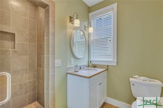 bathroom with a tile shower, vanity, and toilet