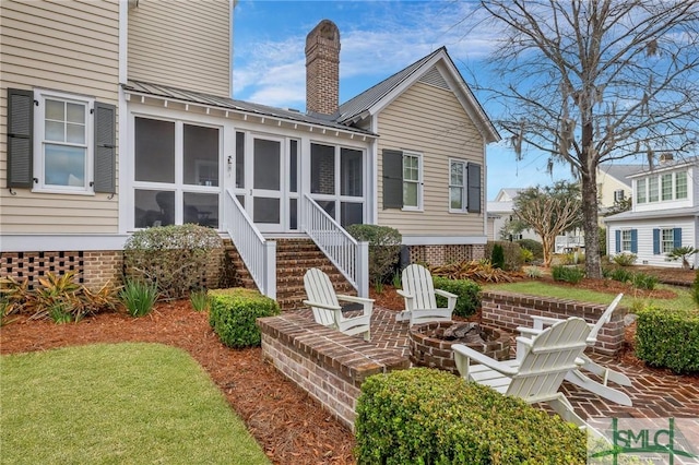 rear view of house with a sunroom and an outdoor fire pit