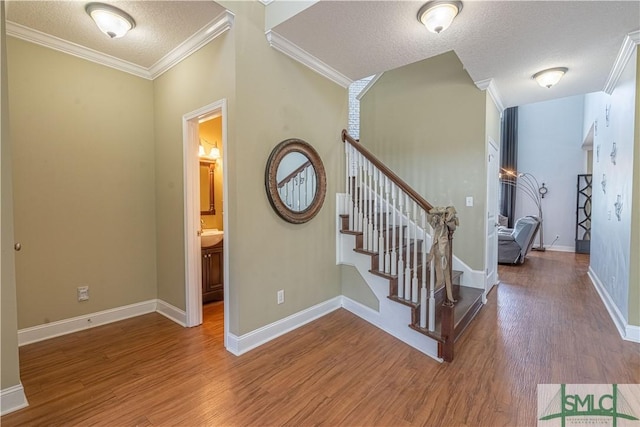 staircase with hardwood / wood-style flooring, crown molding, and a textured ceiling