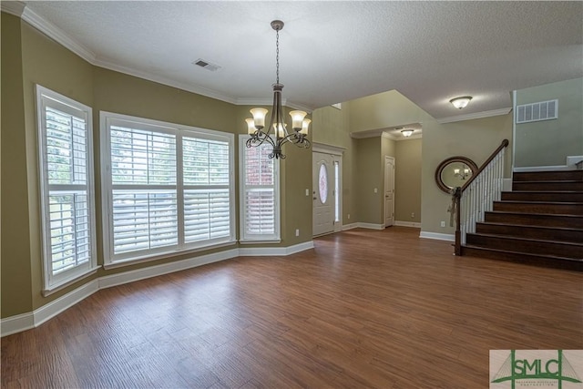 interior space with a textured ceiling, crown molding, dark wood-type flooring, and an inviting chandelier