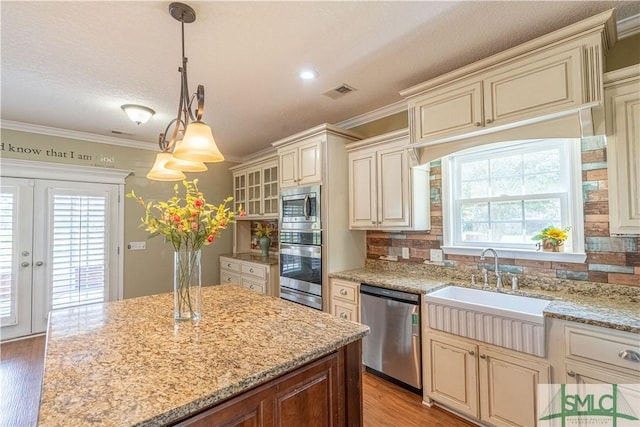 kitchen featuring pendant lighting, tasteful backsplash, appliances with stainless steel finishes, and cream cabinets