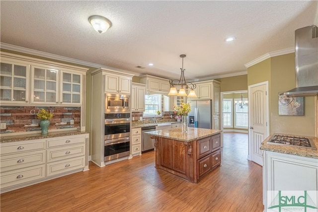 kitchen featuring appliances with stainless steel finishes, decorative light fixtures, a kitchen island, and plenty of natural light