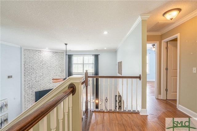 hallway featuring crown molding, brick wall, wood-type flooring, and a textured ceiling