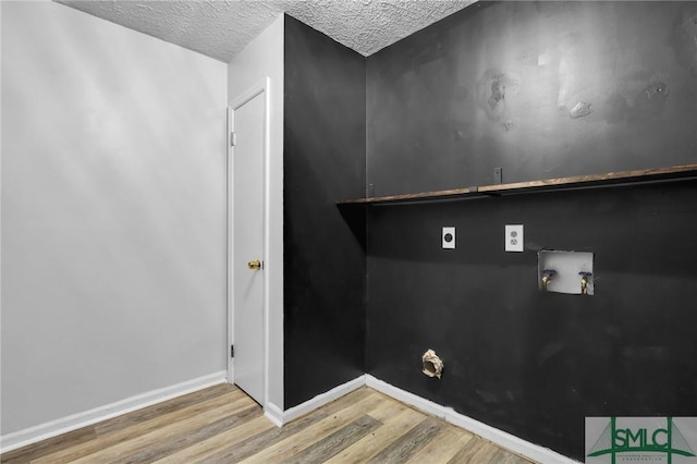 clothes washing area with hookup for an electric dryer, hookup for a washing machine, a textured ceiling, and hardwood / wood-style flooring