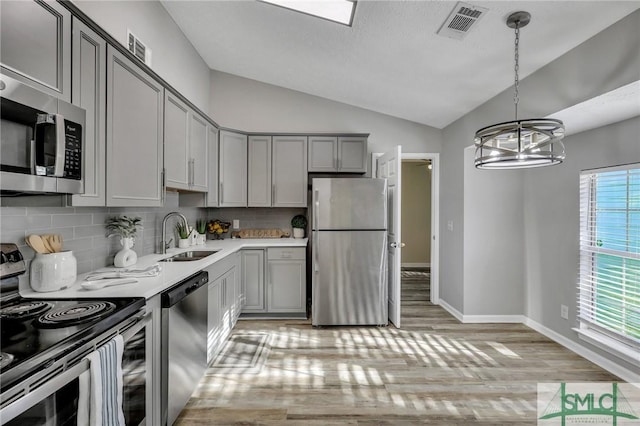 kitchen with gray cabinets, sink, lofted ceiling, and appliances with stainless steel finishes