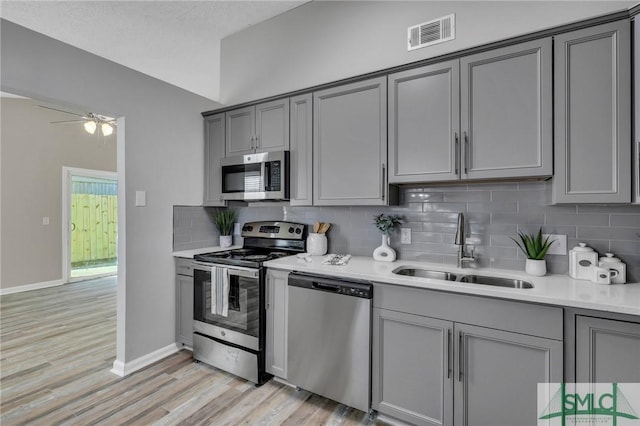 kitchen with gray cabinetry, sink, a textured ceiling, light hardwood / wood-style floors, and stainless steel appliances