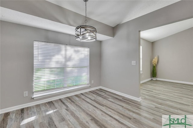 unfurnished room with light hardwood / wood-style floors and a notable chandelier