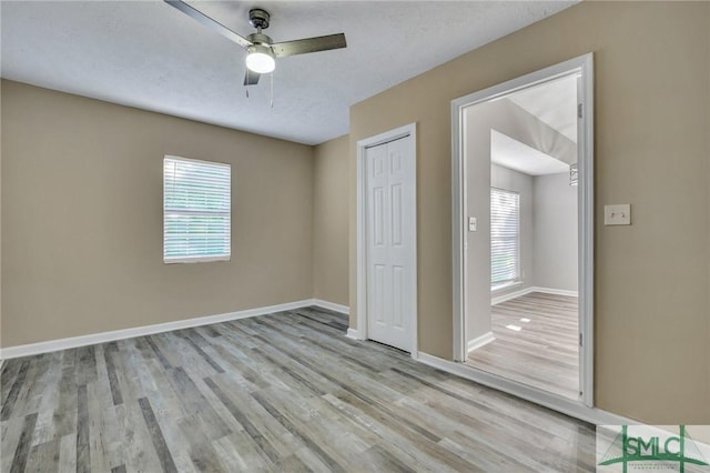 unfurnished bedroom with ceiling fan, a closet, light wood-type flooring, and multiple windows