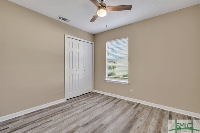 unfurnished bedroom featuring ceiling fan, light wood-type flooring, a textured ceiling, and a closet