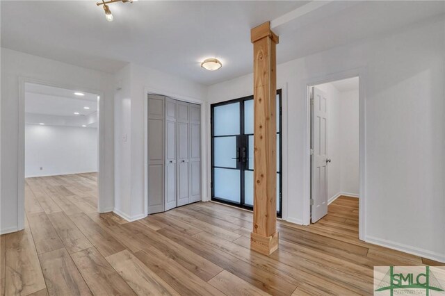 foyer featuring light wood-type flooring and decorative columns