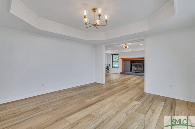 unfurnished living room featuring a tray ceiling, crown molding, and light hardwood / wood-style flooring