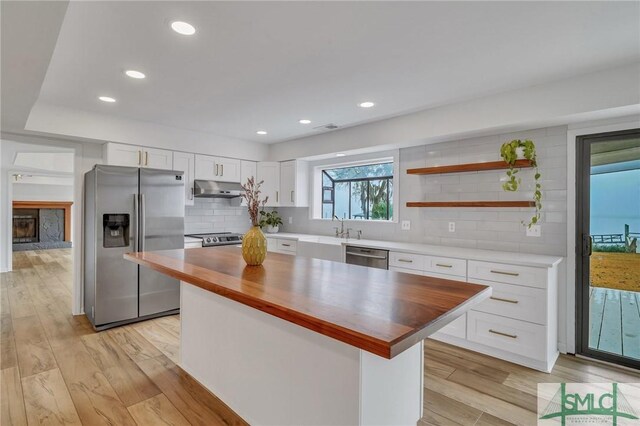 kitchen featuring a center island, white cabinets, light hardwood / wood-style floors, butcher block counters, and stainless steel appliances