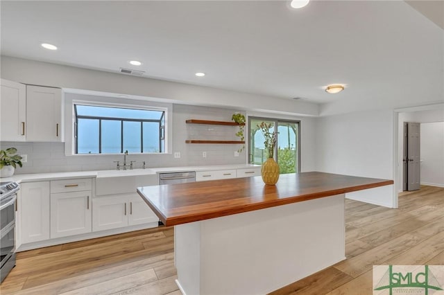 kitchen with wood counters, backsplash, a kitchen island, light hardwood / wood-style floors, and white cabinetry