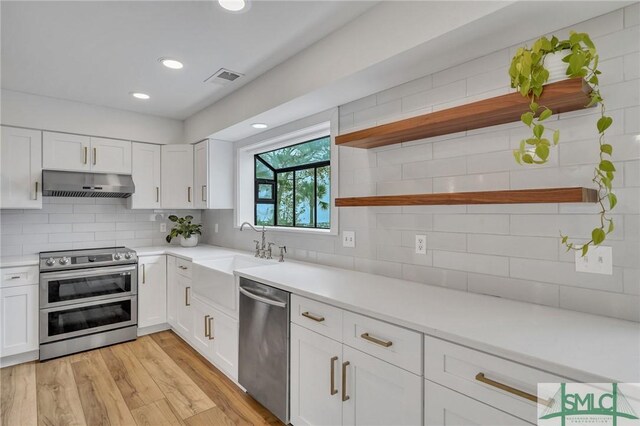 kitchen featuring decorative backsplash, stainless steel appliances, sink, light hardwood / wood-style flooring, and white cabinetry