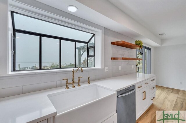 kitchen with dishwasher, backsplash, white cabinets, sink, and light hardwood / wood-style floors