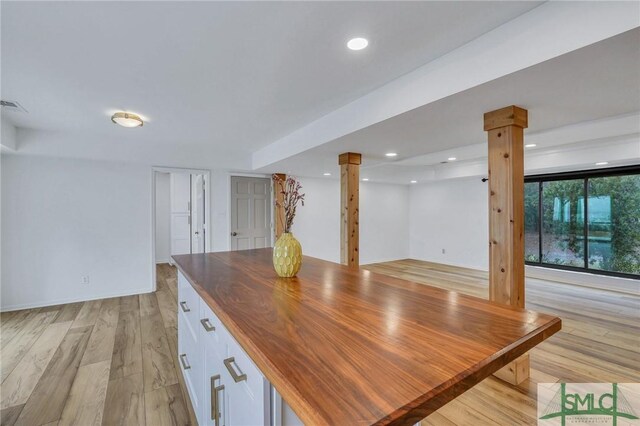 unfurnished dining area with light hardwood / wood-style floors and decorative columns