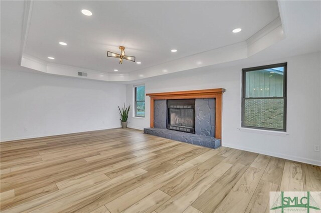 unfurnished living room with a chandelier, a raised ceiling, and light hardwood / wood-style flooring