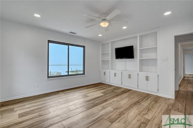 unfurnished living room with ceiling fan, light hardwood / wood-style floors, and built in shelves