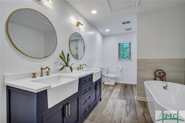 bathroom featuring vanity, a tub to relax in, toilet, and hardwood / wood-style flooring