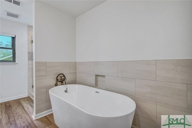 bathroom with a bathtub, tile walls, and hardwood / wood-style flooring