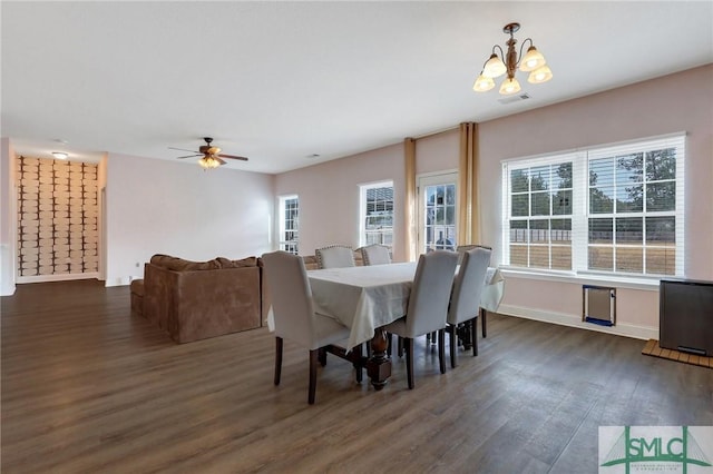 dining area with ceiling fan with notable chandelier and dark hardwood / wood-style floors