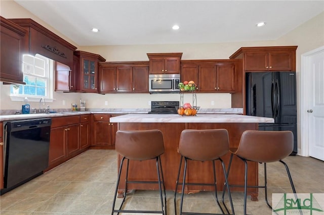 kitchen featuring black appliances, a kitchen island, a kitchen bar, and sink