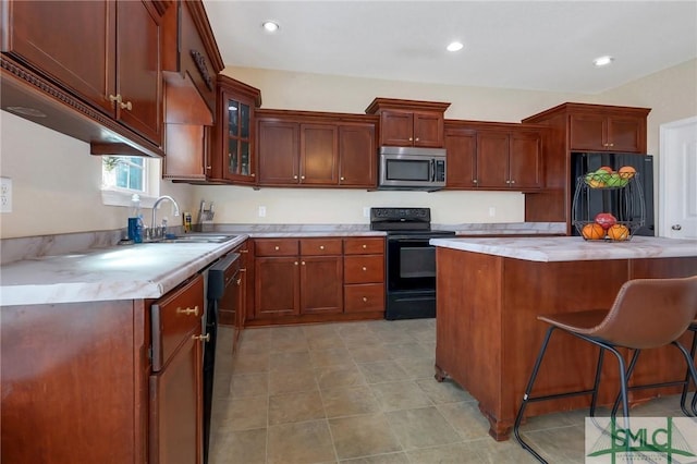 kitchen featuring a kitchen breakfast bar, sink, black appliances, light tile patterned floors, and a kitchen island