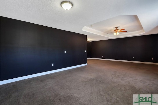 carpeted empty room featuring ceiling fan, a raised ceiling, and a textured ceiling