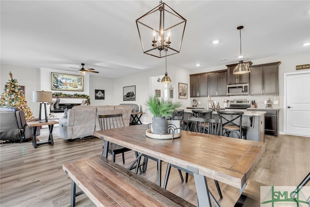 dining room featuring light hardwood / wood-style flooring and ceiling fan with notable chandelier